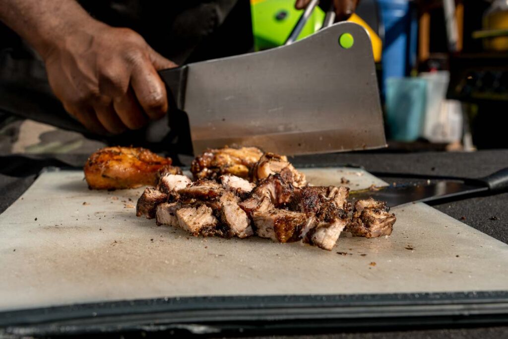 jerk chicken being cut with a cleaver knife for serving